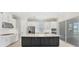 Bright kitchen with a large island, stainless steel appliances, white cabinets, and sliding glass doors to the patio at 15813 San Lazzaro Ave, Bradenton, FL 34211