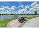 Relaxing lake view from outdoor seating area with paver patio and lush landscaping with bright blue sky at 17817 Pastureland Ave, Lakewood Ranch, FL 34211