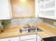 A bright kitchen features white cabinets, butcher block countertops, and a stainless-steel sink at 2155 Wood St # A26, Sarasota, FL 34237