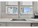 Close up of the kitchen sink with white counter and marble backsplash and windows with neighborhood view at 2500 Boone Ct, Sarasota, FL 34237