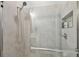Modern bathroom shower featuring gray tile, a glass door, a shower head, and built in shelving at 2500 Boone Ct, Sarasota, FL 34237