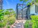 Landscaped backyard featuring a brick path leading to a screened-in patio with comfortable seating and dining at 2525 Daisy Dr, North Port, FL 34289