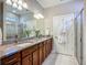 This bathroom shows a double vanity with granite counters, vanity lights, and a walk-in tiled shower at 2525 Daisy Dr, North Port, FL 34289