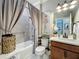 Charming bathroom with tiled shower and tub combo, wood vanity, neutral wall paint, and a decorative mirror at 2525 Daisy Dr, North Port, FL 34289
