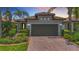 Charming home featuring a brick driveway, a two-car garage, manicured landscaping, and a tile roof at 2525 Daisy Dr, North Port, FL 34289