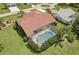 Aerial view of home with tile roof, screened pool, and lush landscaping at 25433 Colon Dr, Punta Gorda, FL 33983