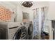 Laundry room with modern washer and dryer, storage rack, decorative curtains, and hanging elephant laundry bag at 2553 Harn Blvd # 1, Clearwater, FL 33764