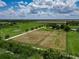 Property aerial showcases well-kept pastures, a gravel drive, and picturesque surroundings under a partly cloudy, sunny day at 26147 L And J Rd, Myakka City, FL 34251