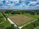 Drone shot of horse property featuring well-maintained pastures, a long driveway, and lush surrounding fields under a bright sky at 26147 L And J Rd, Myakka City, FL 34251