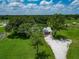 Aerial view of a charming home with mature trees and lush landscaping with a long gravel driveway at 26147 L And J Rd, Myakka City, FL 34251