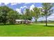 Well-maintained home with a lush green lawn and mature trees offering shade on a sunny day at 26147 L And J Rd, Myakka City, FL 34251