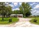 Charming single-story home with a metal roof, garage, spacious front yard, and mature trees on a sunny day at 26147 L And J Rd, Myakka City, FL 34251