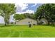 Back of house featuring a well-kept lawn, a storage tank, a picnic table, and lush greenery at 26147 L And J Rd, Myakka City, FL 34251