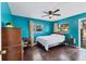 Bright bedroom featuring dark wood floors, a ceiling fan, and windows providing natural light and tree views at 2866 E Rainbow Cir, Sarasota, FL 34231