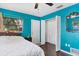 Vibrant bedroom with dark wood floors, an accent wall, closet, a large window, and a queen-sized bed at 2866 E Rainbow Cir, Sarasota, FL 34231