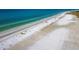Aerial view of a wide sandy beach with sunbathers and colorful lifeguard stands along the blue ocean at 3959 Somerset Dr # 5, Sarasota, FL 34242