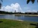 Picturesque view of a tranquil pond surrounded by lush greenery and tan condos under a partly cloudy sky at 4016 Oakview Dr # J6, Punta Gorda, FL 33980