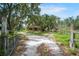Scenic driveway leading to a charming two-story home surrounded by mature trees at 5034 257Th E St, Myakka City, FL 34251