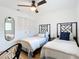 Bright bedroom with two twin beds, ceiling fan, wood floor, and black framed mirror at 516 Parkdale Mews # 516, Venice, FL 34285