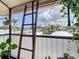 Relaxing screened porch features string lights, a wooden ladder, and plants providing a cozy atmosphere at 516 Parkdale Mews # 516, Venice, FL 34285