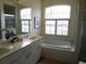 Bright bathroom with double vanity, soaking tub under a window, and neutral color palette at 5449 Downham Mdws, Sarasota, FL 34235