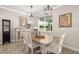 A formal dining area with a wood table, white chairs, modern light fixture, and bright window at 5750 Long Shore Loop, Sarasota, FL 34238