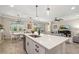 An open-concept kitchen with a large island, pendant lighting, stainless steel appliances, and an adjacent living area at 5750 Long Shore Loop, Sarasota, FL 34238