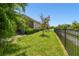 Fenced backyard with a well-manicured lawn, palm tree, and shrubbery at 5802 Alabaster Stone Ln, Apollo Beach, FL 33572