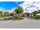 Exterior view of a community clubhouse with lush landscaping, palm trees, and a circular driveway at 5910 Hevena Ct, Palmetto, FL 34221
