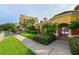 Welcoming entrance to the community with vibrant landscaping, a building with tiled roof and gated access to the pool at 610 Riviera Dunes Way # 306, Palmetto, FL 34221