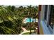Overhead view of a community swimming pool surrounded by lush landscaping and palm trees at 610 Riviera Dunes Way # 306, Palmetto, FL 34221