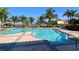 A large community swimming pool with lounge chairs surrounded by tropical palm trees and waterfront views at 610 Riviera Dunes Way # 306, Palmetto, FL 34221