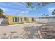 Bright yellow home with a shell driveway, covered carport, and tidy, low-maintenance landscaping at 627 Avenida Del Norte, Sarasota, FL 34242