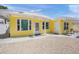 Close up of a bright yellow home with white trim, shell driveway, and small covered porch at 627 Avenida Del Norte, Sarasota, FL 34242