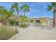 Charming yellow home featuring tropical landscaping, a covered carport, and a white shell driveway at 627 Avenida Del Norte, Sarasota, FL 34242