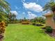 Well-maintained backyard with manicured lawn, palm trees, and lush landscaping at 6851 Bay Hill Dr, Lakewood Ranch, FL 34202