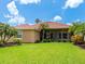 Expansive backyard featuring lush green grass, tropical foliage, and a charming home exterior with a red tile roof at 6851 Bay Hill Dr, Lakewood Ranch, FL 34202