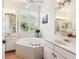 Bright bathroom featuring a soaking tub, dual vanities, and plantation shutters for natural light at 6851 Bay Hill Dr, Lakewood Ranch, FL 34202