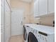 Bright laundry room with washer, dryer, overhead cabinets, and closet storage at 6851 Bay Hill Dr, Lakewood Ranch, FL 34202