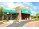 Charming stone and stucco restaurant featuring a green awning, outdoor seating, and lush landscaping at 6851 Bay Hill Dr, Lakewood Ranch, FL 34202