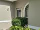 Inviting front entrance with neutral stucco, front door, arched window, and manicured landscaping at 6908 Stoneywalk Ct, Bradenton, FL 34203