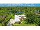 Stunning aerial view of home with lush landscaping, white roof, circular driveway, and serene lake backdrop at 7404 Weeping Willow Blvd, Sarasota, FL 34241