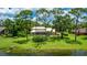 Expansive backyard with mature trees, lush green lawn, screened lanai, and beautiful lake view at 7404 Weeping Willow Blvd, Sarasota, FL 34241