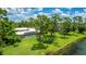 Spacious backyard featuring a screened-in pool, lush lawn, mature trees, and a serene lake backdrop at 7404 Weeping Willow Blvd, Sarasota, FL 34241