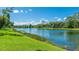 Scenic lake view with lush green grass, mature trees, and blue skies with puffy white clouds on a sunny day at 7404 Weeping Willow Blvd, Sarasota, FL 34241