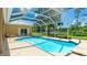 Backyard screened-in pool with a spa, and views of the lawn and lake beyond the house at 7404 Weeping Willow Blvd, Sarasota, FL 34241