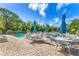 Community pool with tables, chairs, and umbrellas on brick surface surrounded by lush greenery at 7866 Eagle Creek Dr # 7866, Sarasota, FL 34243