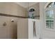 Modern shower stall featuring tiled walls, glass door and arched window at 8102 Waterview Blvd, Lakewood Ranch, FL 34202