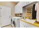 Functional laundry room with modern appliances, ample storage, and a utility sink with yellow countertop at 8102 Waterview Blvd, Lakewood Ranch, FL 34202