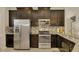Modern kitchen featuring stainless steel appliances, dark cabinetry, and a stylish backsplash at 8417 Karpeal Dr # 4, Sarasota, FL 34238